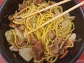 Chicken yakisoba or SÃÂsu yakissoba with vegetables in a black bowl with chopsticks Royalty Free Stock Photo